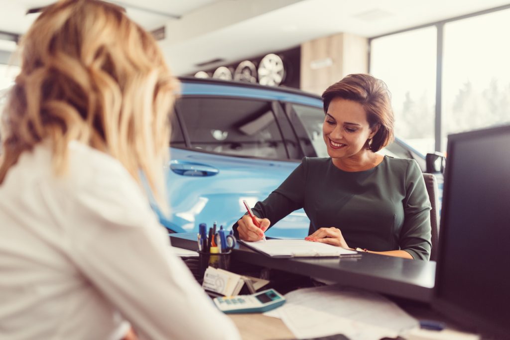 Woman signing papers at a dealership