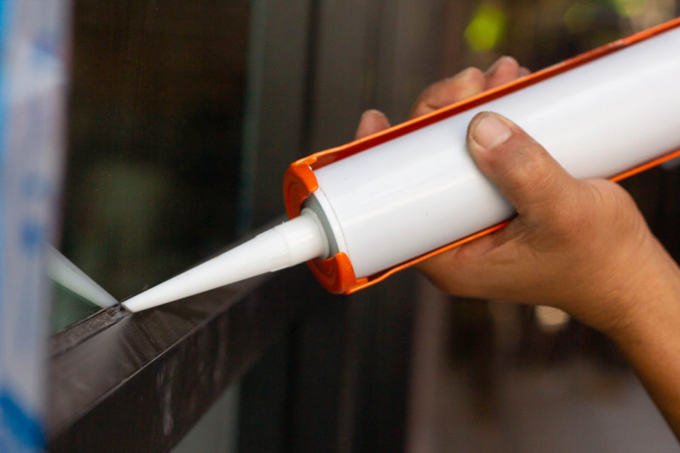 The craftsman's hand uses silicone glue and glue to weld the glass and aluminum.