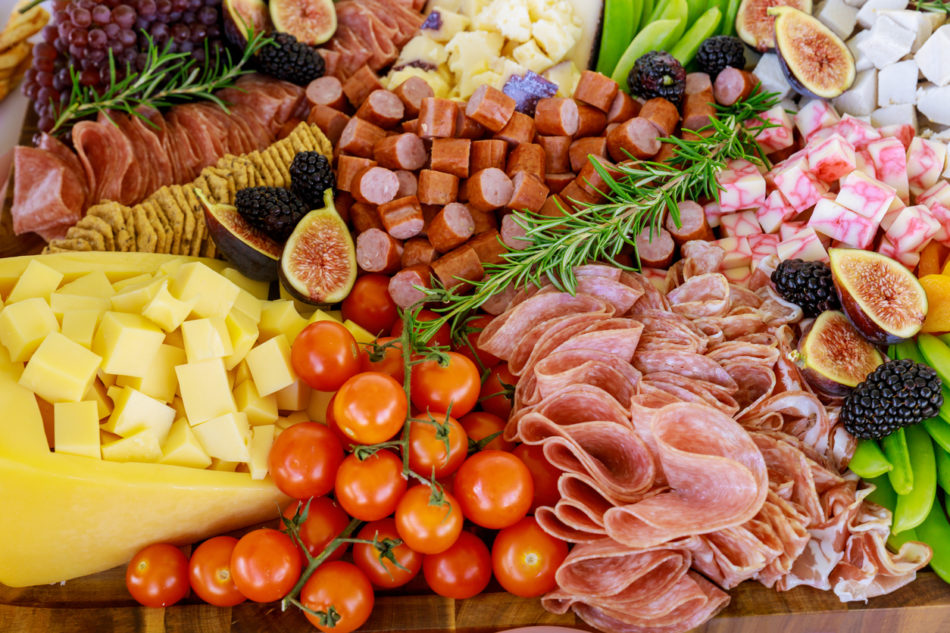 Party table with cut fruit, ham and cheese.