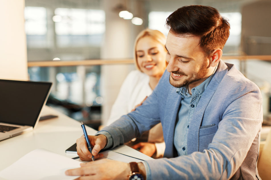 Young business couple signing a contract