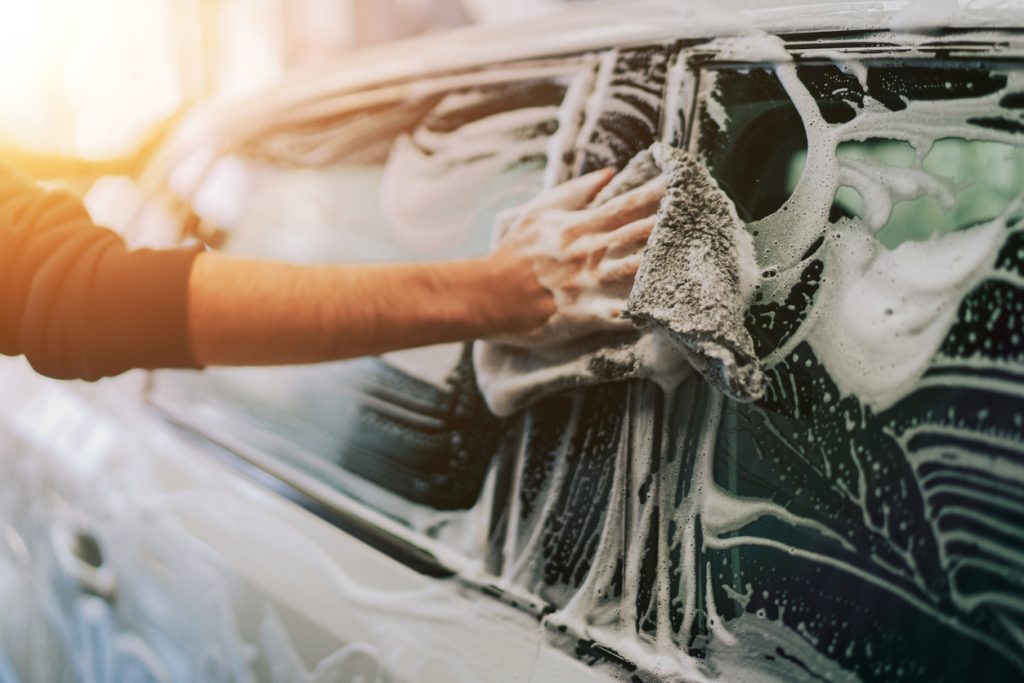 A person using a cloth to was a soapy car