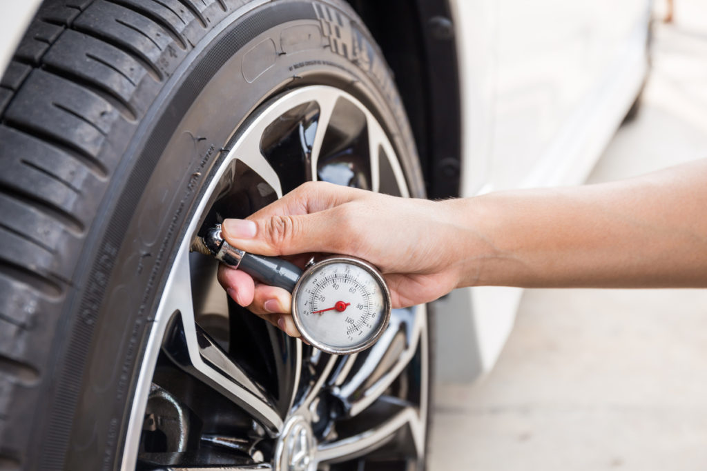 Close-Up Of Hand holding pressure gauge for car tire pressure measurement