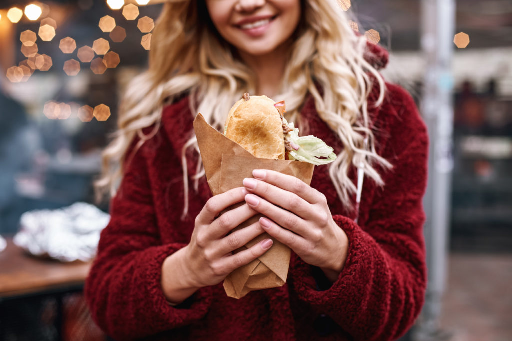 Woman with sandwich outdoors.