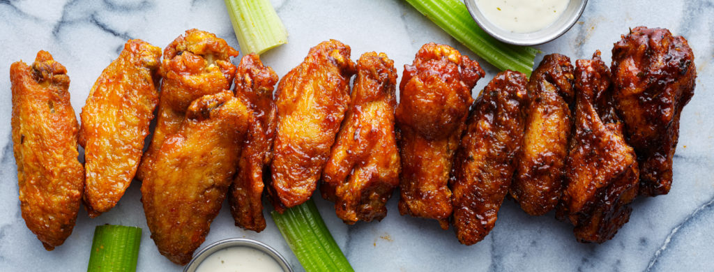 line of buffalo chicken wings drenched in different sauces top