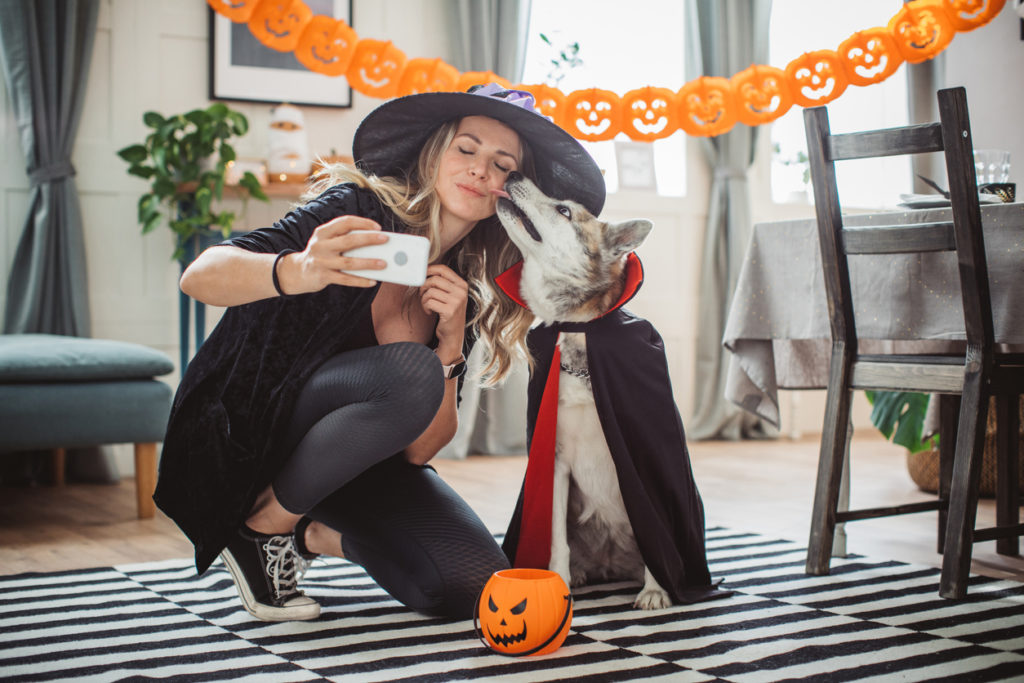 Woman and her pet dog wearing costumes at home