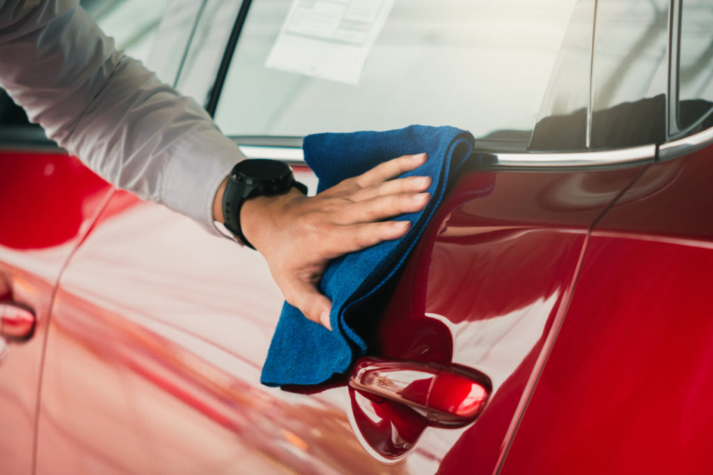 man cleaning the exterior of vehicle