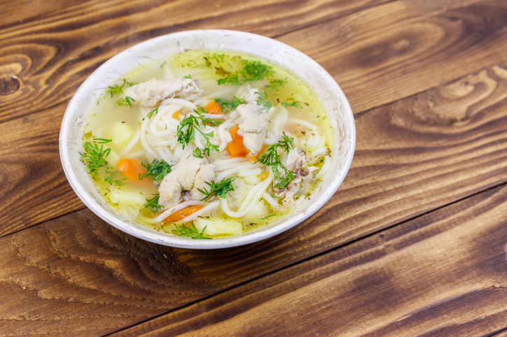 Chicken soup with noodles and vegetables on wooden table