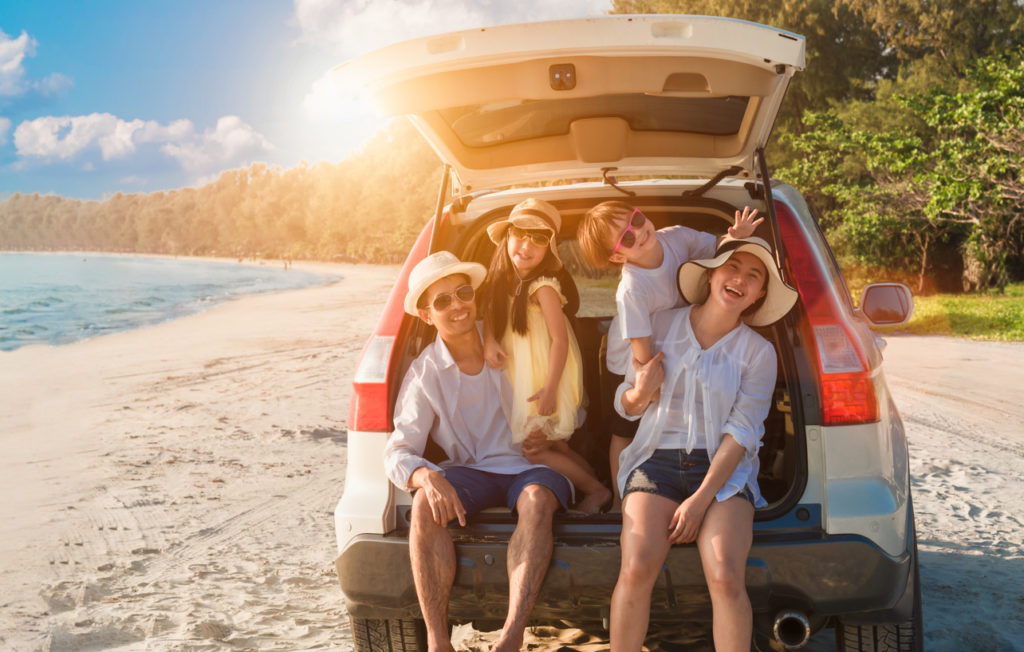 Happy family fun travel on road trip in vacation at beach. Father, mother, daughter, son with enjoying on hatchback in seaside in summer holiday.